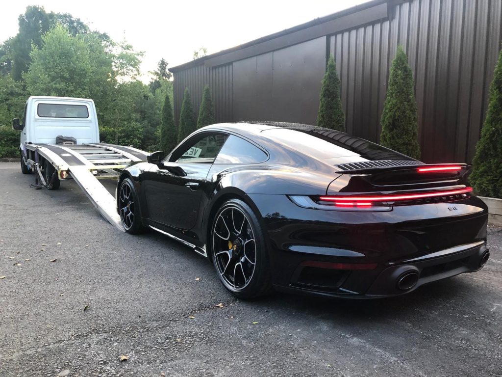 Luxury black Porsche 911 turbo being loaded by AK Car Transport