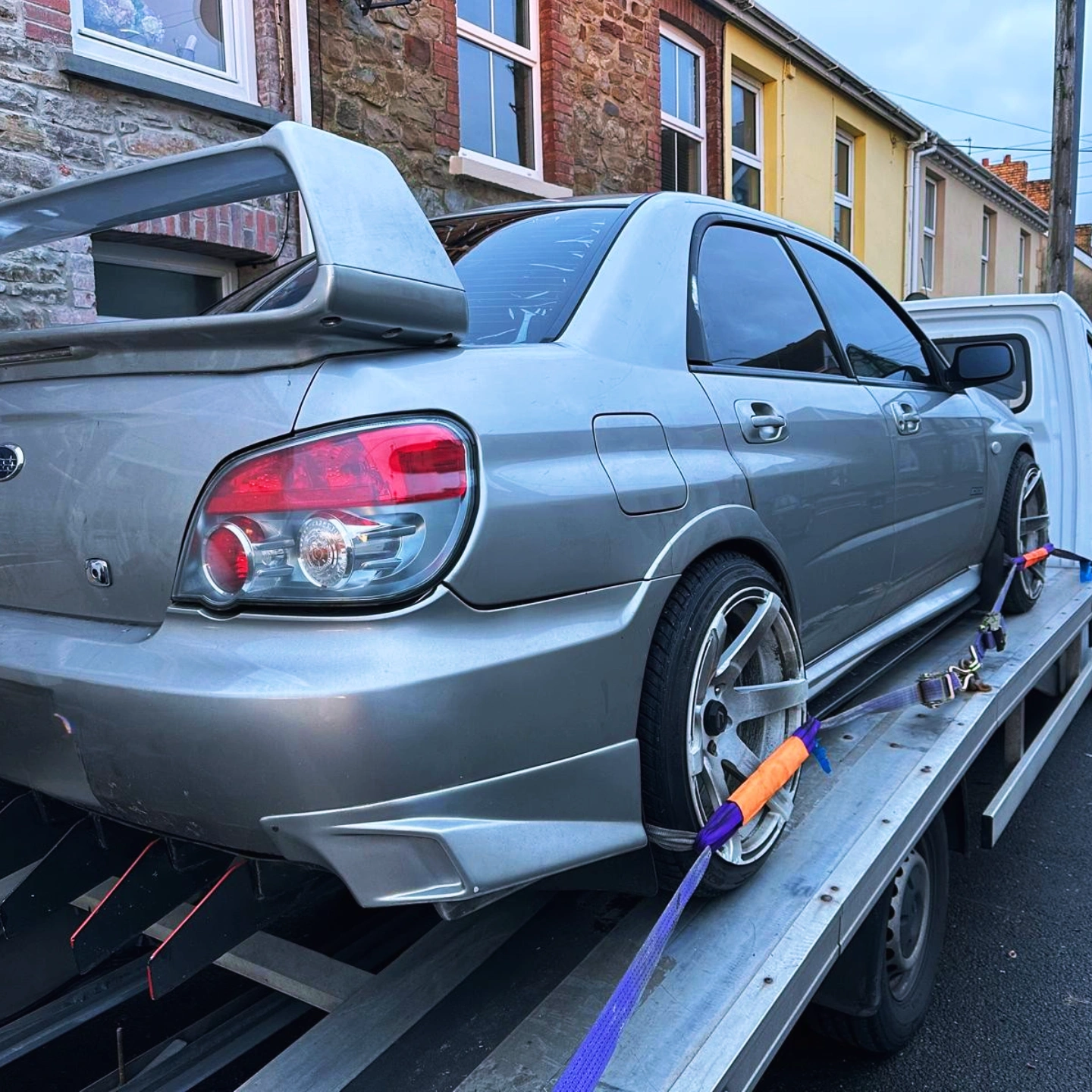 Recovery trucking towing a silver subaru